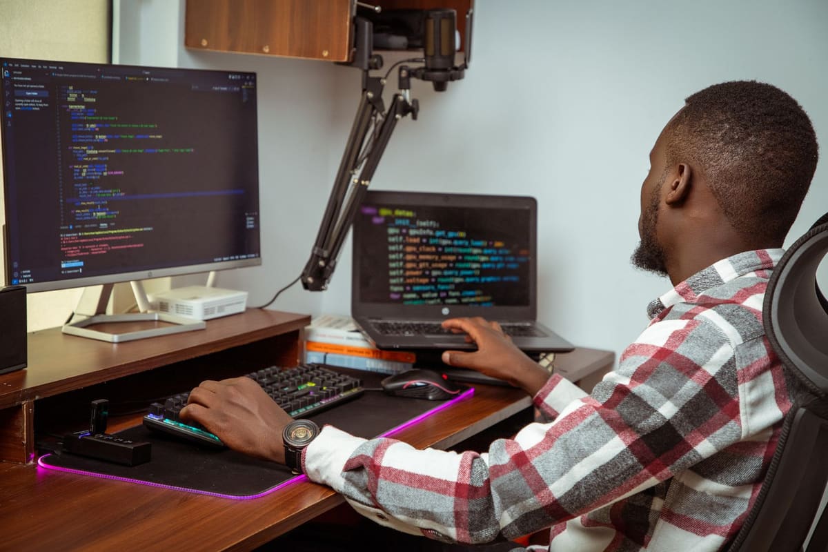 Software developer writing code on two screens in a Nairobi office